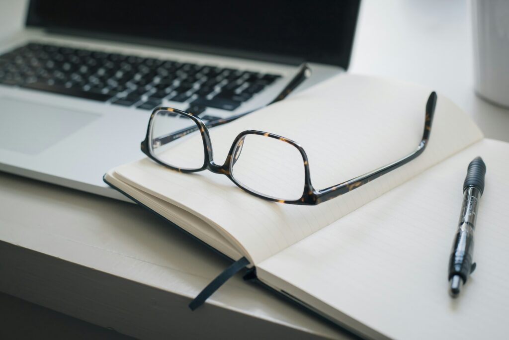 Laptop on the desk with a book and glasses for website accessibility